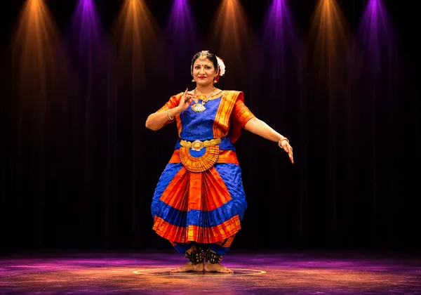 Bharatanatyam student in an expressive raised-arm pose on stage at Spotlight Academy, The Woodlands TX