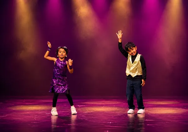 Two young Bollywood Dance students performing on a spotlit stage at Spotlight Academy, Spring & The Woodlands TX