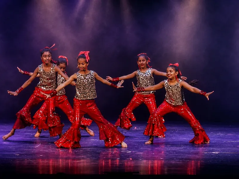 Bollywood Dance students in red and gold costumes performing a group routine at Spotlight Academy, Spring & The Woodlands TX