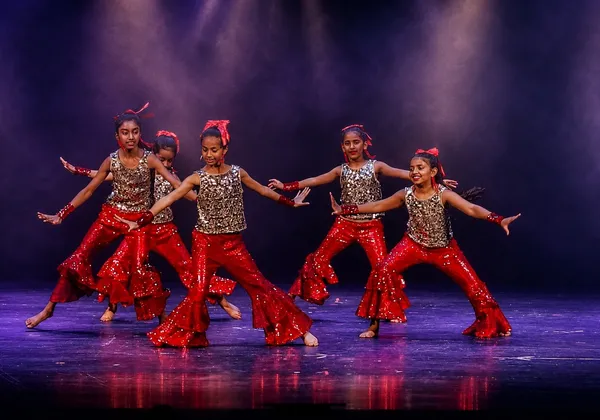 Bollywood Dance students in red and gold costumes performing a group routine at Spotlight Academy, The Woodlands TX