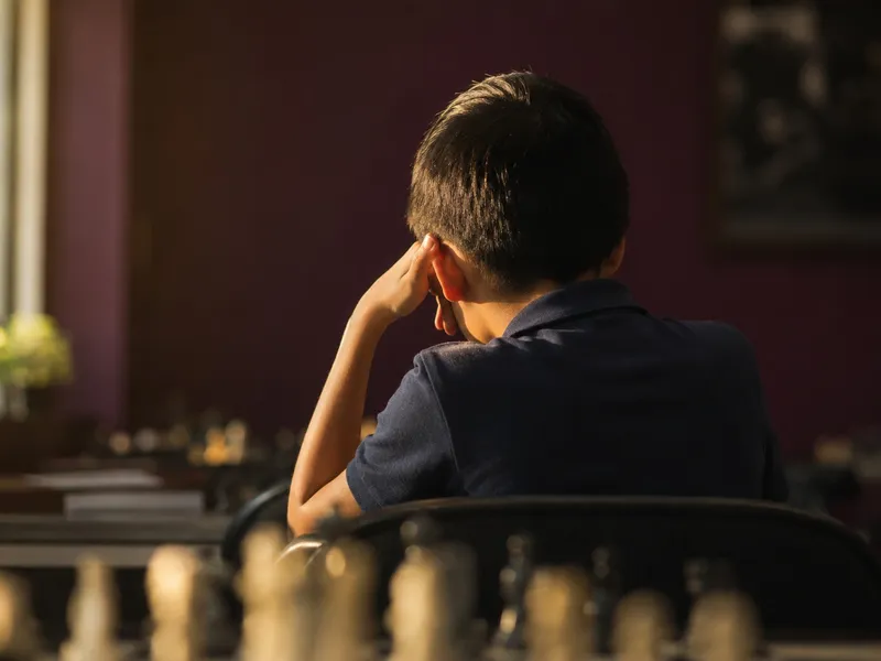Young chess player seen from behind thinking over a board, Spotlight Academy chess classes in Spring & The Woodlands TX