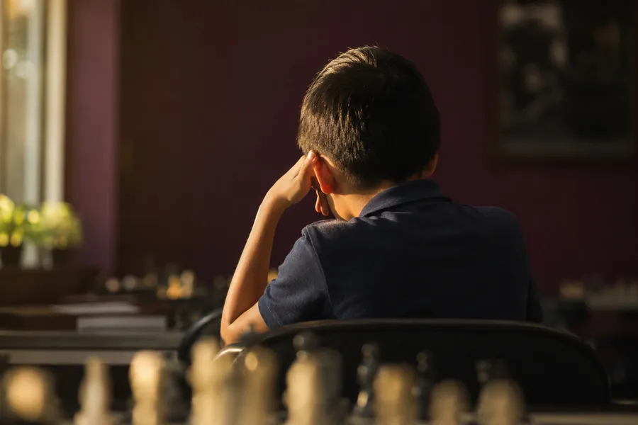 Young chess player seen from behind thinking over a board, Spotlight Academy chess classes in Spring and The Woodlands TX